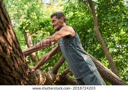 Man rests on a tree trunk and preparing doing push ups around the nature