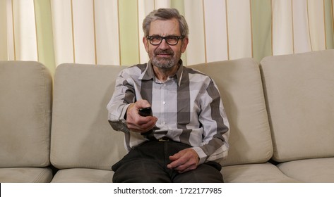 Man retiree switches the TV remote control channels while sitting on the couch.