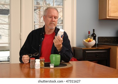 A Man Of Retirement Age Reading The Label Of A Vitamin Bottle