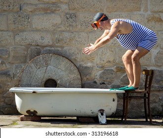 man in retro swimsuit jumps to the outdoor bathtub. Funny fat swimmer in retro style jumps into the tub. Vintage style swimwear man starting swim in bathtub.Man with snorkel train jump into the water.