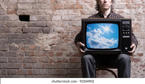 A Man With A Retro TV In The Hands Of A Sunny Sky Image On The Screen.