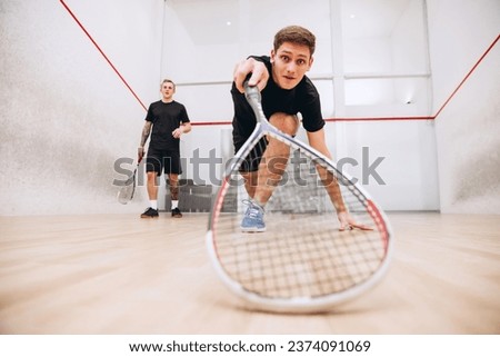 Man returning ball. Portrait of two boys training together, playing squash isolated over sport studio background. Concept of active life, team game, energy, sport, competition. Copy space for ad