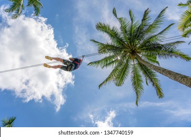 Man Ride On Zip Line In The Tropical Jungle. Tourist Ride On Zipline In The Rainforest Of Island Bali Near Rice Terrase, Ubud, Indonesia