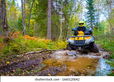 A Man Rides Along A Muddy Forest Road On An ATV. Riding In The Woods On A Quad Bike. Racing Through The Forest On A Quad Bike. Extreme Rest. Rent An ATV.