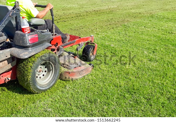 A\
man rides a lawn mower. Lawn Care. Riding Mower.\
Grass