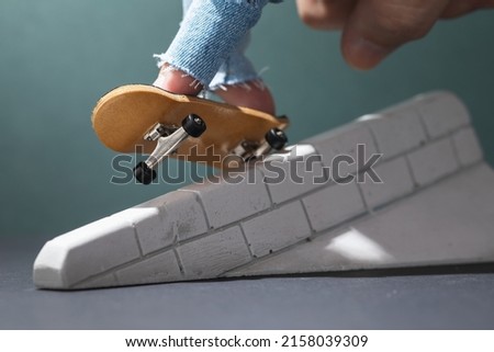 A man rides a small fingerboard on a plaster ramp