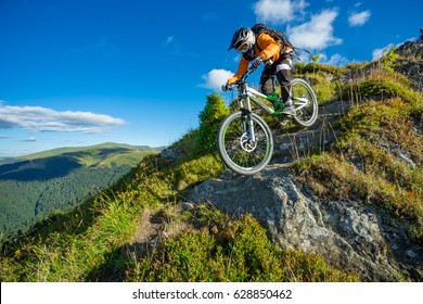 A Man Is Riding Bicycle, On The Background Of Mountains And Blue Sky. Beautiful Summer Day. Mountain Bike Race