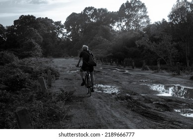 Man Riding Bike In Rural Damaged Road With Muds And Holes, Black And White Image