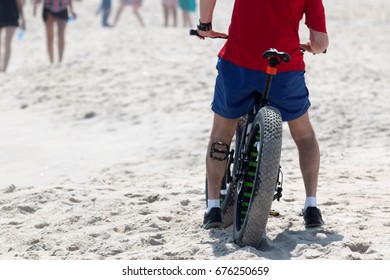 A Man Riding His Fat Wheel Bike On The Sand At The Beach Takes A Break