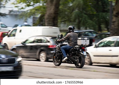 Man Riding A Motorbike In Busy City Street Trafic On Tram Track, From Behind