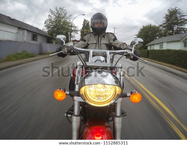 Man\
riding a motorcycle in the streets during a rainy day. Taken in\
Surrey, Greater Vancouver, British Columbia,\
Canada.