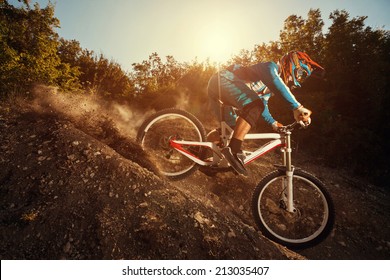 Man riding a mountain bike in downhill style at sunrise. Extreme sports on a bicycle. - Shutterstock ID 213035407