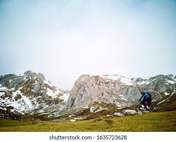 Man Riding A Mountain Bike In The Snowy Mountains, Wears A Mountain Bike And Winter Clothes, Helmet And Safety Protections