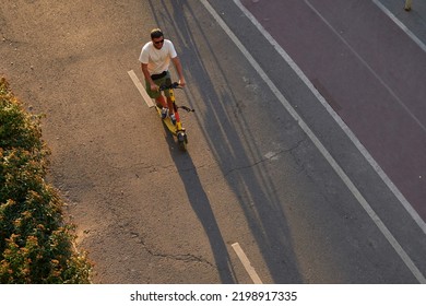 Man Is Riding On Kick Scooter On Cycling Road. Top Aerial View.