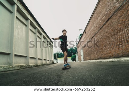 Similar – Young man riding on skate and holding surfboard