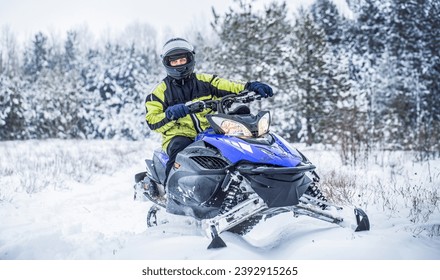Man is riding snowmobile in mountains. Pilot on a sports snowmobile in a mountain forest. Athlete rides a snowmobile in the mountains. Snowmobile in snow. Concept winter sports.