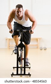 Man Riding Stationary Bicycle In Health Club