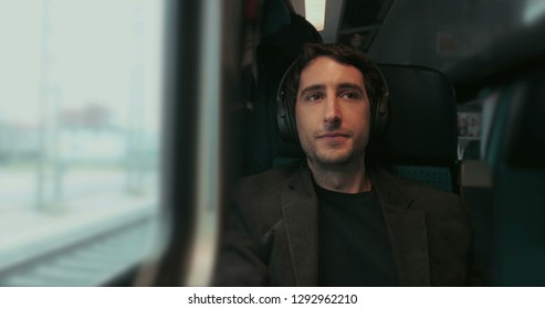 Man Riding Train Putting Headphones On