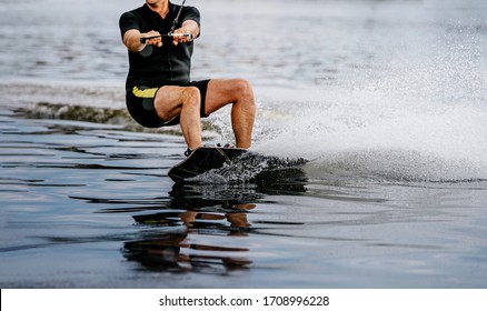 man riding wakeboard on lake behind boat