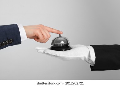 Man ringing butler service bell on grey background, closeup