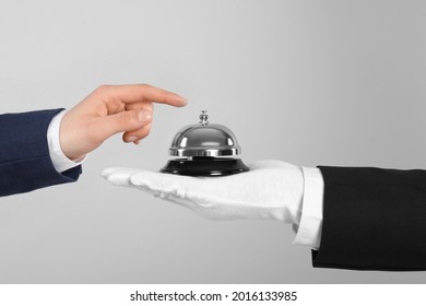 Man ringing butler service bell on grey background, closeup
