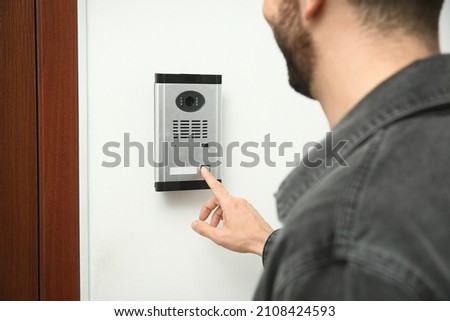 Man ringing intercom with camera in entryway, closeup