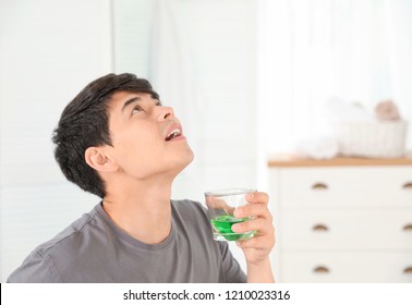 Man Rinsing Mouth With Mouthwash In Bathroom. Teeth Care