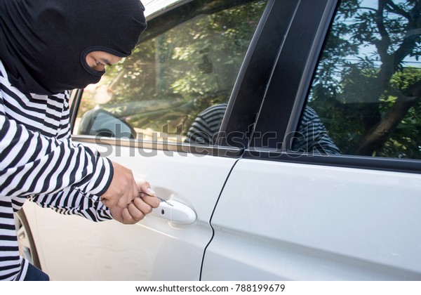 The\
man robber with a balaclava on his head trying to break into the\
car/Selective focus/Criminal and car thief\
concept