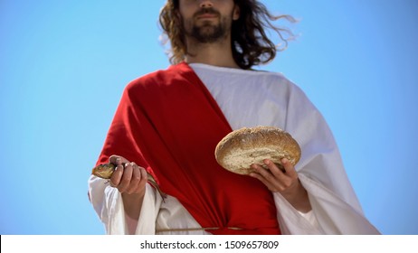 Man in robe holding fish and bread, charity concept to feed hungry, generosity - Shutterstock ID 1509657809
