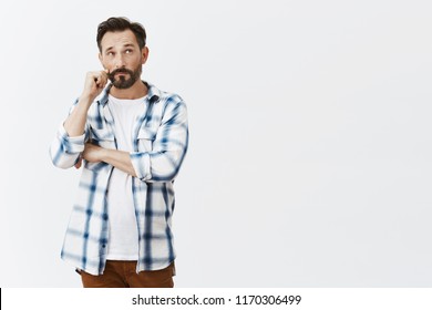 Man Rolling Moustache While Looking Up With Serious And Thoughtful Expression, Thinking, Making Choice Or Deciding Something In Mind, Talking With Conscience, Standing Over Gray Background