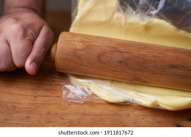 Man With Rolling Pin Stretches Butter For Preparation With Fat Inside A Transparent Bag. Smelly Kitchen