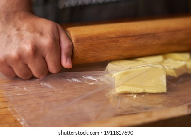 Man With Rolling Pin Stretches Butter For Preparation With Fat. Smelly Kitchen