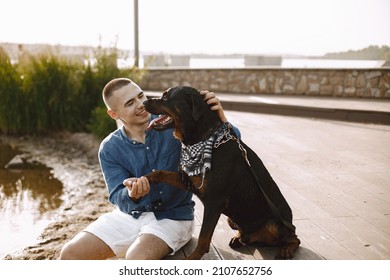 Man With Rotweiller Dog Playing Together Near The Lake