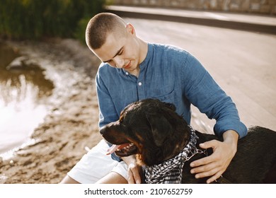 Man With Rotweiller Dog Playing Together Near The Lake