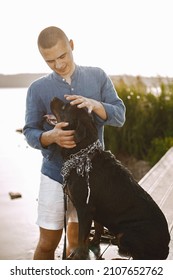 Man With Rotweiller Dog Playing Together Near The Lake