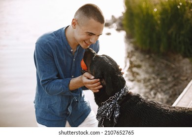 Man With Rotweiller Dog Playing Together Near The Lake