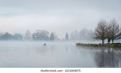 Man Rowing A Boat On The Lake, Heavy Fog Drifting On The Lake. 