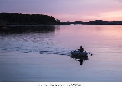 Man Rowing A Boat In Sunset