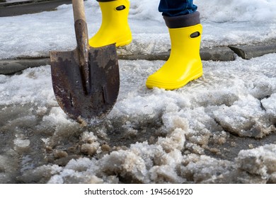 Man In Rubber Boots Clean Meerschaum Track Of Old Snow. He Hits A Dirty Wet Snow Shovel So He Quickly Melted