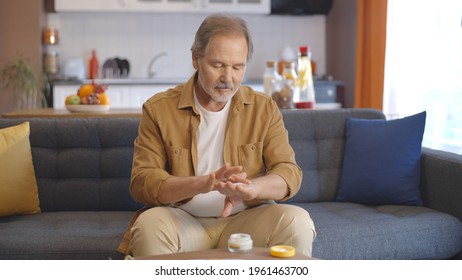 The man rubing skin cream on his hands looks at the screen with pleasure. The concept of loving skin cream. - Shutterstock ID 1961463700