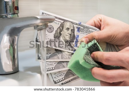 a man rubs a sponge hundred dollar bill. Money Laundering, Concept. washing off of money on the black market. Banknotes of 100 dollars in the hands of men near water jets in washbasin.