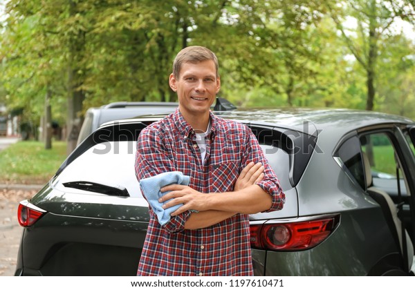 Man with rug near\
washed car outdoors