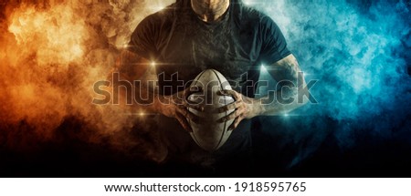 Man rugby player holds ball on dark background. Sports banner. Horizontal copy space background