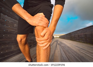 Man runner holding his painful knee because of injury. Injury from workout and exercising