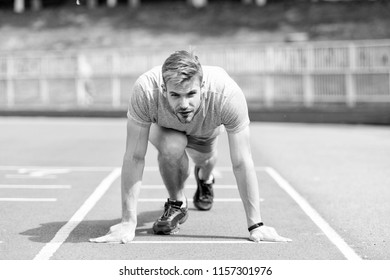 Man runner on start position at stadium. Runner in start pose on running surface. Man run outdoor at running track. Sport and athletics concept. Sportsman on concentrated face ready to go.