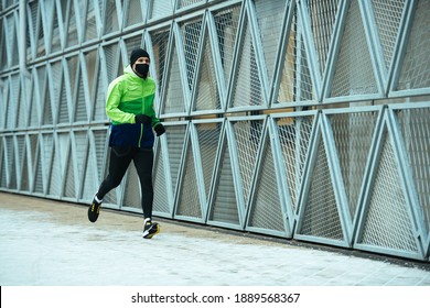 Man Runner Wearing Face Mask. Training During Covid-19 Pandemic. Winter Exercise To Stay Fit. Urban City Jogger. Smiling Man Fitness Workout. Active And Healthy Life In Quarantine 