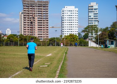 Man Running Across The Lawn Of A City Football Field. Street Race. Amateur Sport Concept.