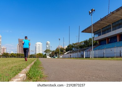 Man Running Across The Lawn Of A City Football Field. Street Race. Amateur Sport Concept.