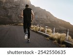 Man, running back and mountain fitness to sprint, road and outdoor for endurance challenge. Male person, sports workout and cardio for marathon training, athlete and morning exercise for health