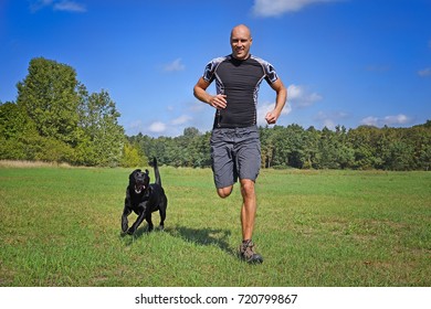 Man Running With Dog In The Park At Sunny Day.